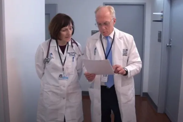 Doctors walking together and looking at a document in a hallway