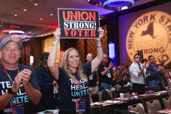 Woman holding a sign that says "union strong voter" at a convention